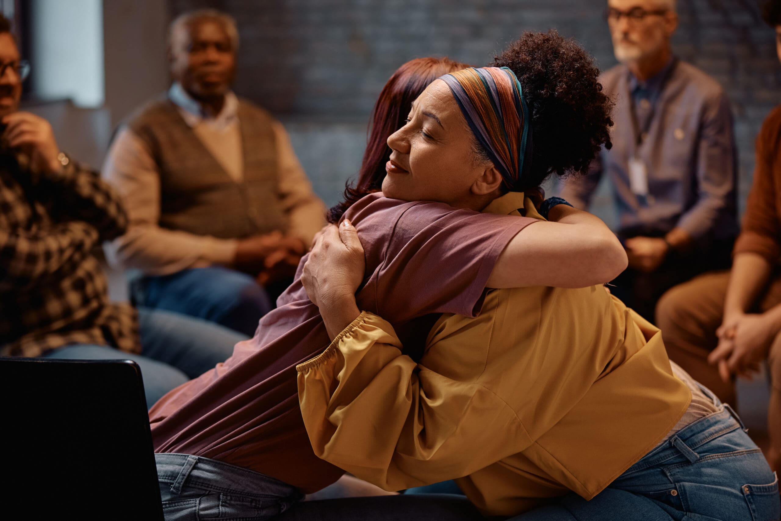 Peer support group participants sharing encouragement and connection during a mental health recovery program.